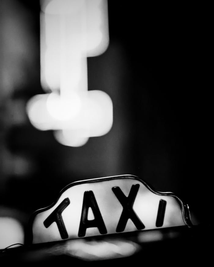gallery-1 Close-up of a classic taxi sign at night in a city environment, black and white photo.