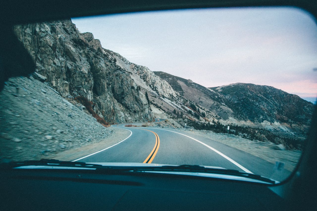 services-01 View of a winding mountain road through a car windshield during a road trip.