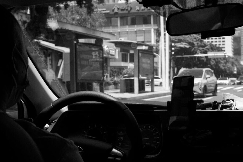 pexels photo 33472489 Monochrome photo of a taxi driver navigating a city street in broad daylight.